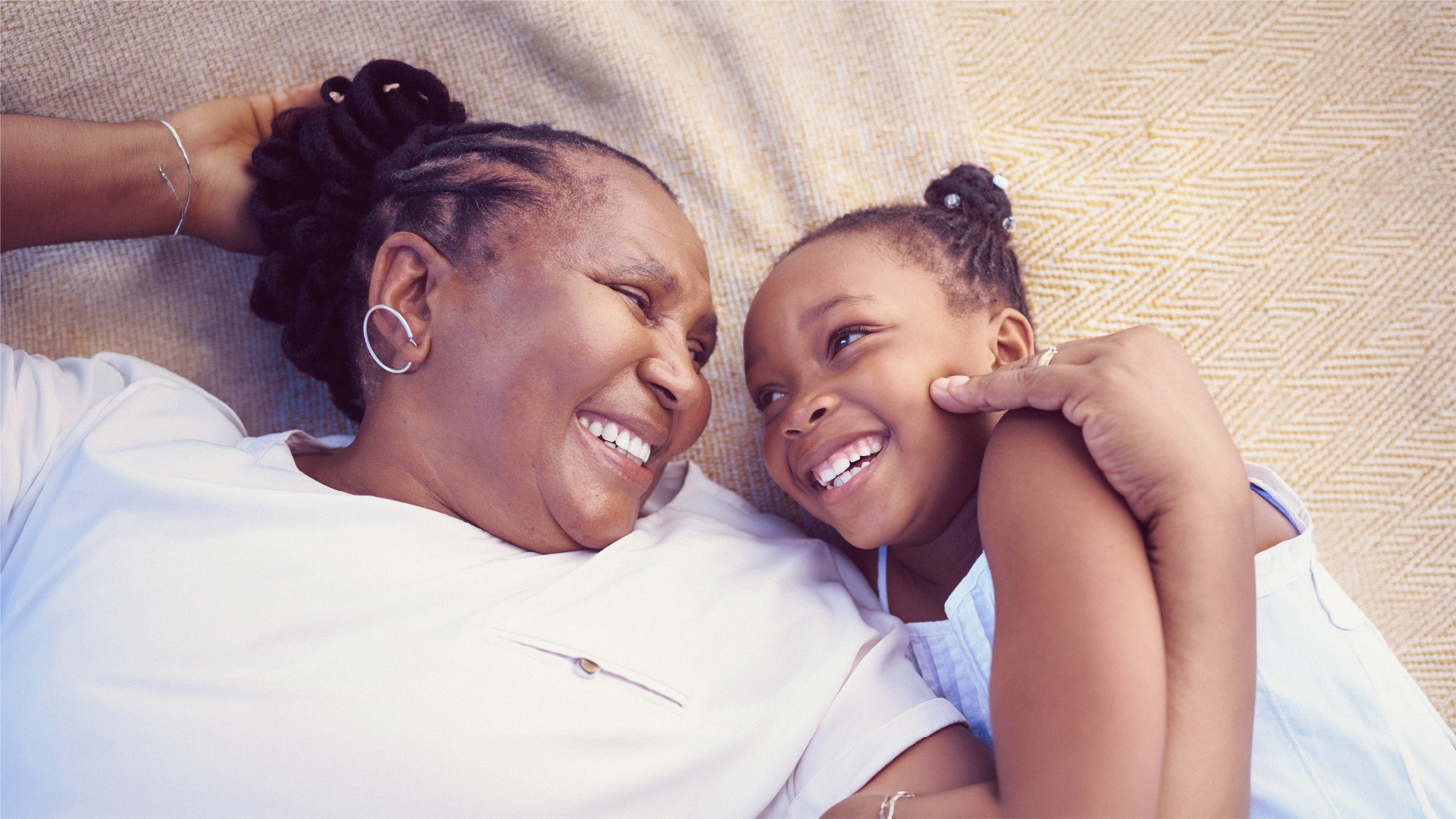 A grandmother and her granddaughter lying together, laughing
